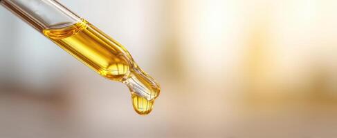 The pipette with golden oil dropping against a blurred background. photo