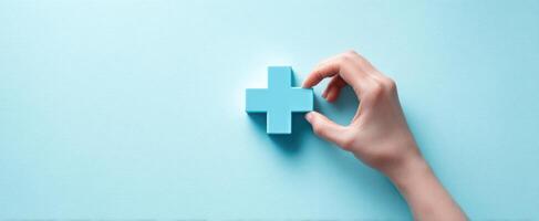 The hand placing a blue medical cross symbol on a clean background. photo