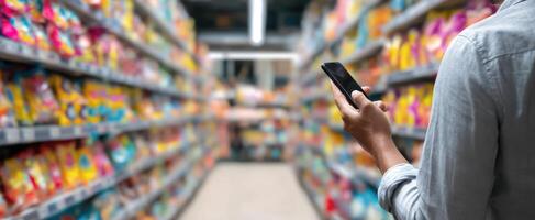 The shopper using a smartphone in a vibrant grocery aisle. photo