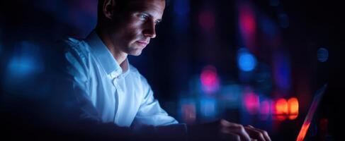 The focused individual working on a laptop in a vibrant, illuminated environment. photo