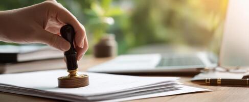 The hand applying a seal to important documents in a modern workspace. photo