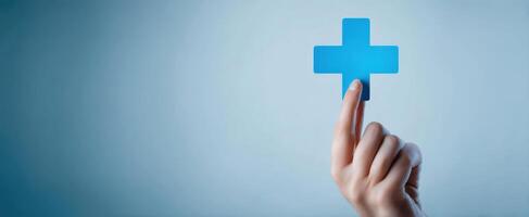 The hand pointing at a blue medical plus sign against a serene background. photo