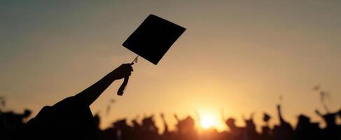 The joyful moment of graduation with caps raised against a stunning sunset. photo