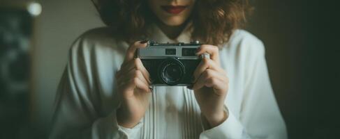The woman holding a vintage camera in a soft-lit environment. photo