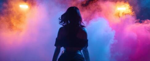 The silhouette of a woman illuminated by vibrant smoke and colorful lights. photo
