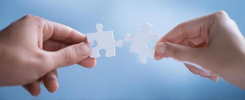 The Hands Connecting White Puzzle Pieces on a Soft Blue Background. photo