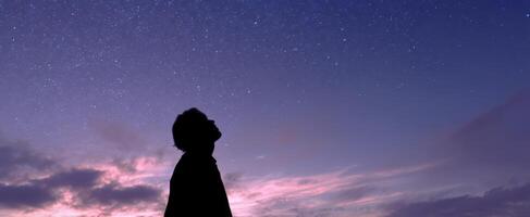 The silhouette of a person gazing at a starry night sky. photo