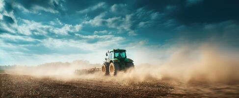 The tractor working in the field creates a cloud of dust against the sky. photo