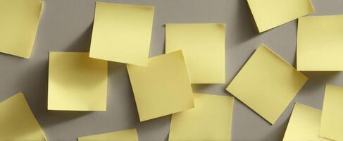 The scattered arrangement of yellow post-it notes on a grey background. photo