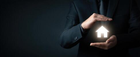 The businessman protecting a glowing home symbol in his hands. photo