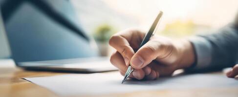 The focused hand writing with a pen on a sheet of paper in an office. photo