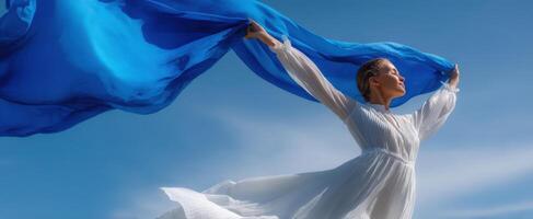 The graceful woman in a flowing blue fabric against a beautiful sky. photo