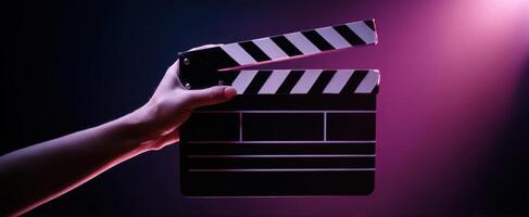 The clapperboard held in a hand against a colorful background of light. photo