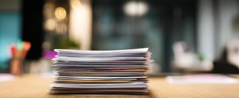 The organized stack of papers on a wooden desk in a contemporary office setting. photo