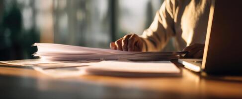 The person organizing paperwork at a modern workspace in soft lighting. photo