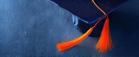 The Graduation Cap with Orange Tassel on a Blue Background photo