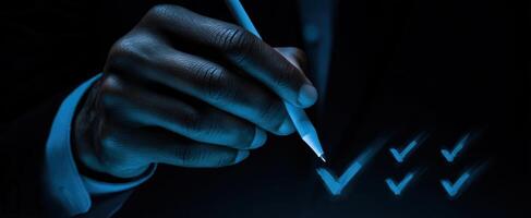 The hand writing checkmarks on a document with a sleek pen in blue light. photo