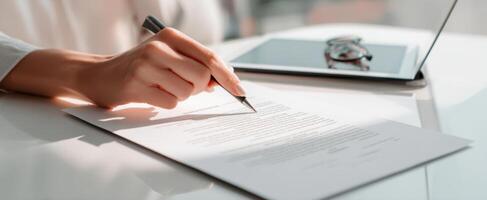 The hand signing a document at a modern office workspace with technology. photo
