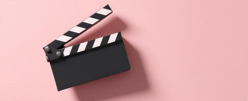 The classic clapperboard against a vibrant pink background for filmmaking. photo