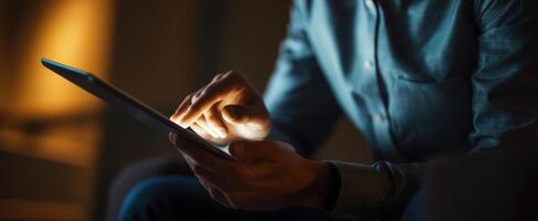 The individual using a tablet in a cozy, dimly lit environment. photo