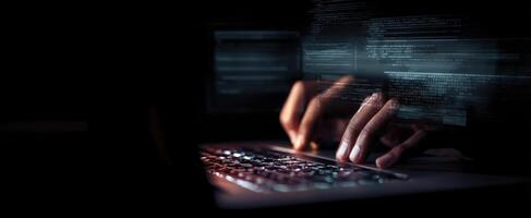 The focused hands typing code on a laptop in a dark environment. photo