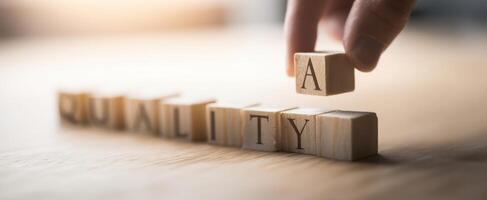 The hand placing the letter A in the wooden blocks spelling quality photo