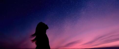 The silhouette of a woman gazing at the starry night sky. photo