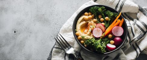 The vibrant bowl of fresh vegetables and nutritious hummus on a textured background. photo