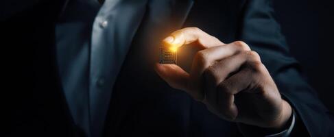 The businessman holding a glowing microchip in a dark environment. photo