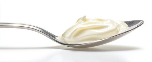 The smooth cream beautifully perched on a silver spoon against a white background. photo