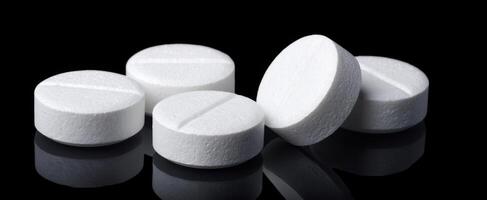 The collection of white tablets reflecting elegantly on a black surface. photo