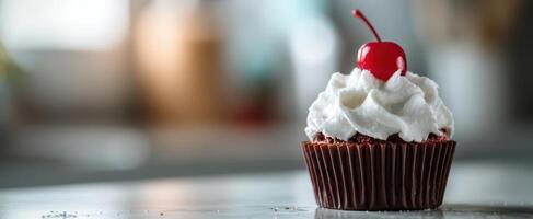 The tempting chocolate cupcake topped with whipped cream and a bright cherry. photo