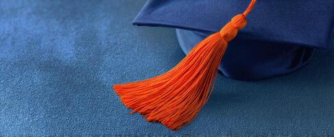 The vibrant orange tassel on a blue graduation cap symbolizing academic achievement. photo