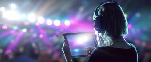 The woman enjoying a concert while capturing the moment on her tablet. photo