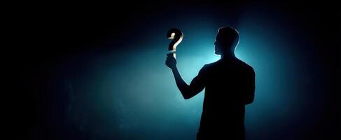 The silhouette holding a question mark in a dramatic light setting. photo