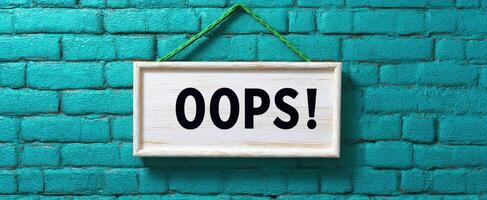 The Oops Sign Hanging on a Vibrant Teal Brick Wall photo