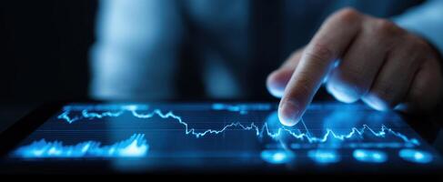 The hand interacting with financial data on a digital touchscreen tablet. photo