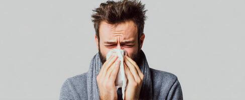 The man expressing discomfort while dealing with a cold and using a tissue. photo