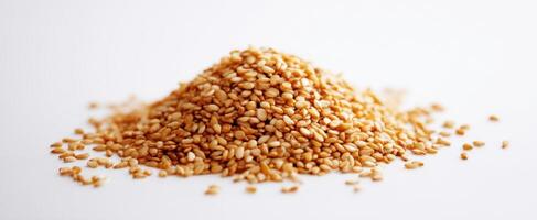 The golden pile of sesame seeds on a white background. photo