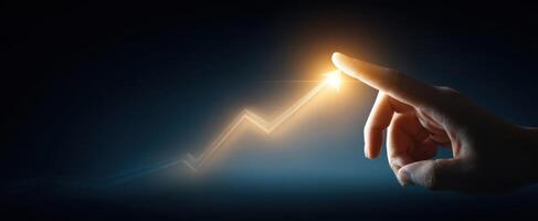 The hand pointing towards a glowing upward trend in a dark backdrop. photo
