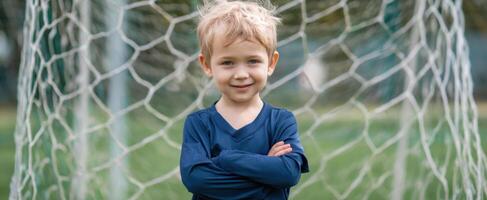 The confident young boy standing proudly in front of a soccer goal. photo
