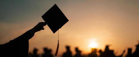 The graduation cap held high against a beautiful sunset backdrop. photo