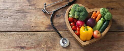 The heart-shaped bowl filled with fresh vegetables and a stethoscope for health. photo