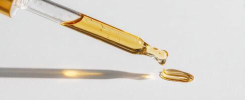 The dropper releasing golden oil onto a pristine surface. photo
