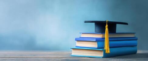 The graduation cap rests atop a stack of blue books symbolizing academic achievement. photo