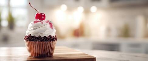 The delicious cupcake topped with whipped cream and a cherry against a cozy kitchen backdrop. photo
