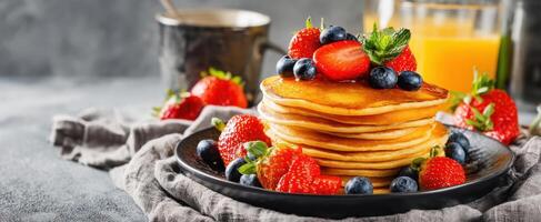 The delicious stack of pancakes topped with fresh strawberries and blueberries. photo