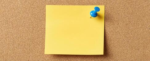 The yellow sticky note pinned on a corkboard surface for reminders photo