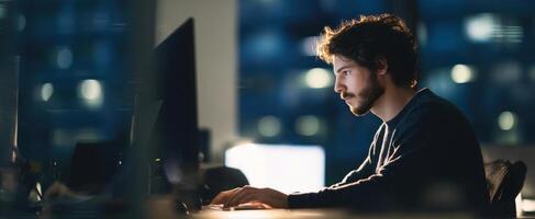 The focused man working on a computer in a modern office at night. photo