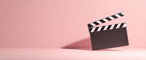 The classic clapperboard sits elegantly on a soft pink backdrop photo
